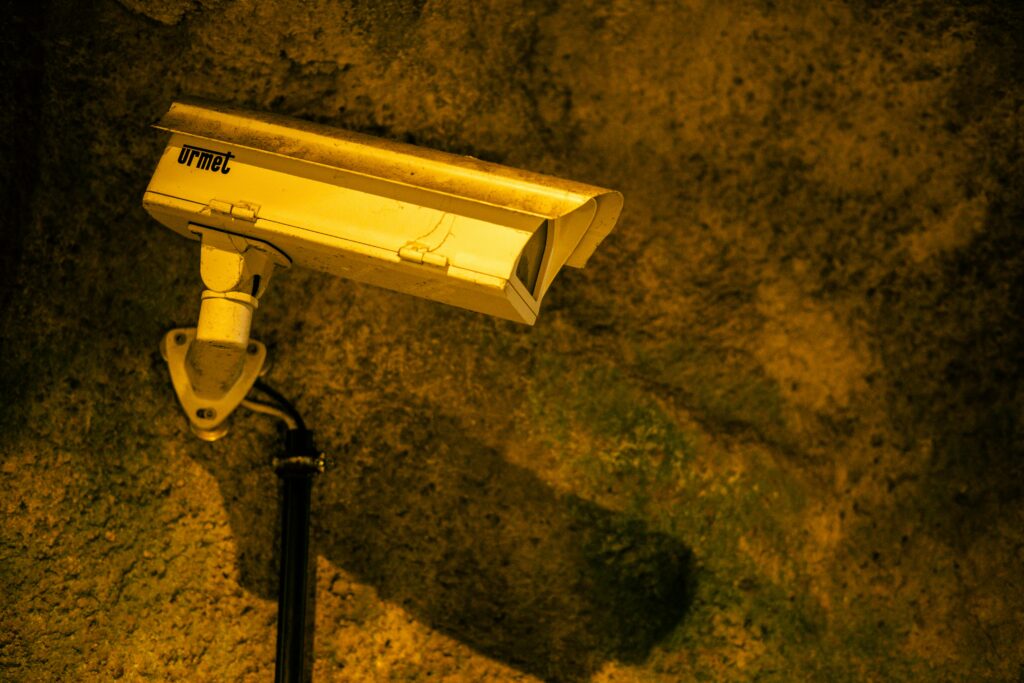 Close-up of a security camera mounted on a textured wall at night.